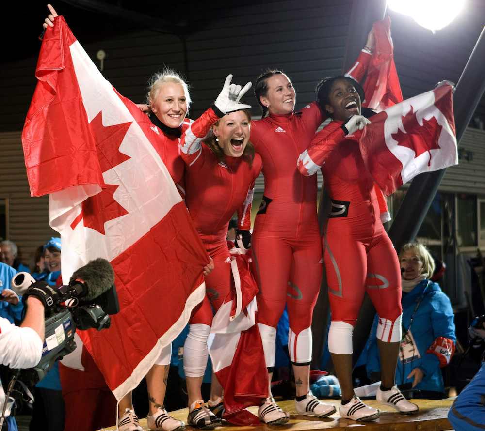 Les quatre Canadiennes célèbrent et portent plusieurs drapeaux canadiens
