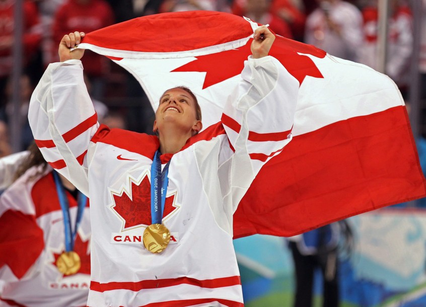 Kim St-Pierre, médaille au cou et tenant le drapeau du Canada