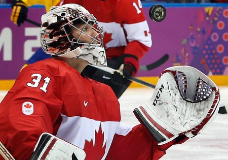 Sochi Olympics Ice Hockey Men Un gardien de but de hockey sur glace tente d'effectuer un arrêt