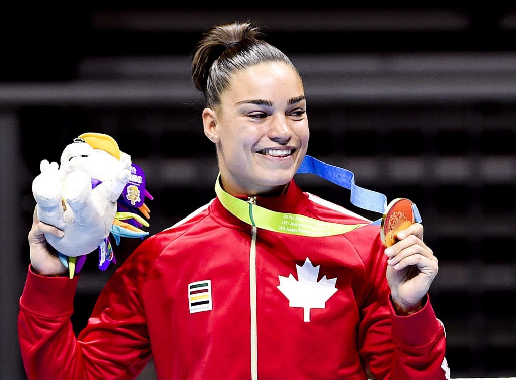 Une boxeuse montre sa médaille sur le podium