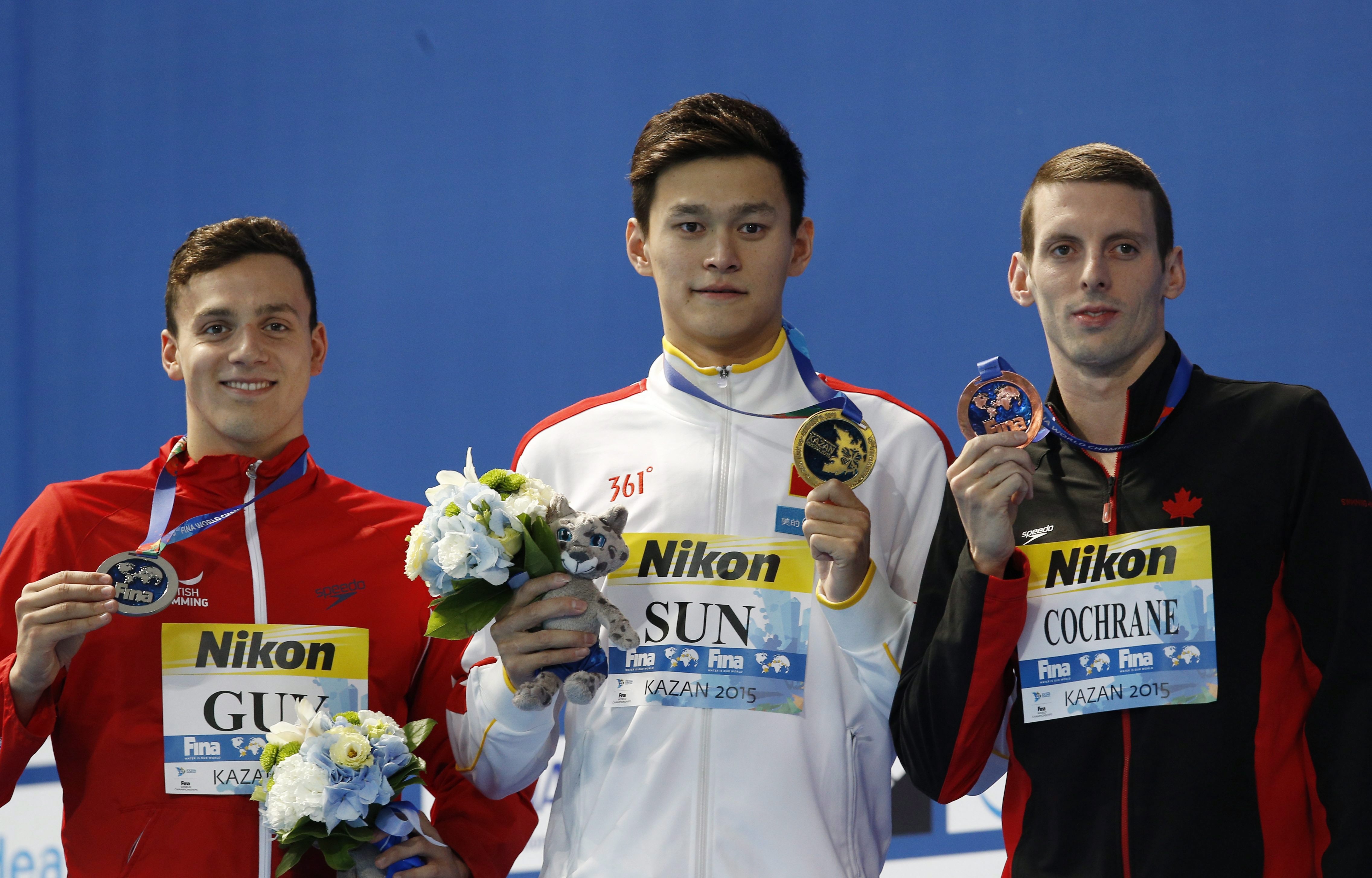 Ryan Cochrane en compagnie du Chinois Sun Yang (au centre) et de l'Anglais James Guy durant la cérémonie des médailles de l'épreuve du 400 m style libre aux Championnats du monde aquatique de la FINA à Kazan, en Russie, le 2 août 2015. (AP Photo/Sergei Grits)