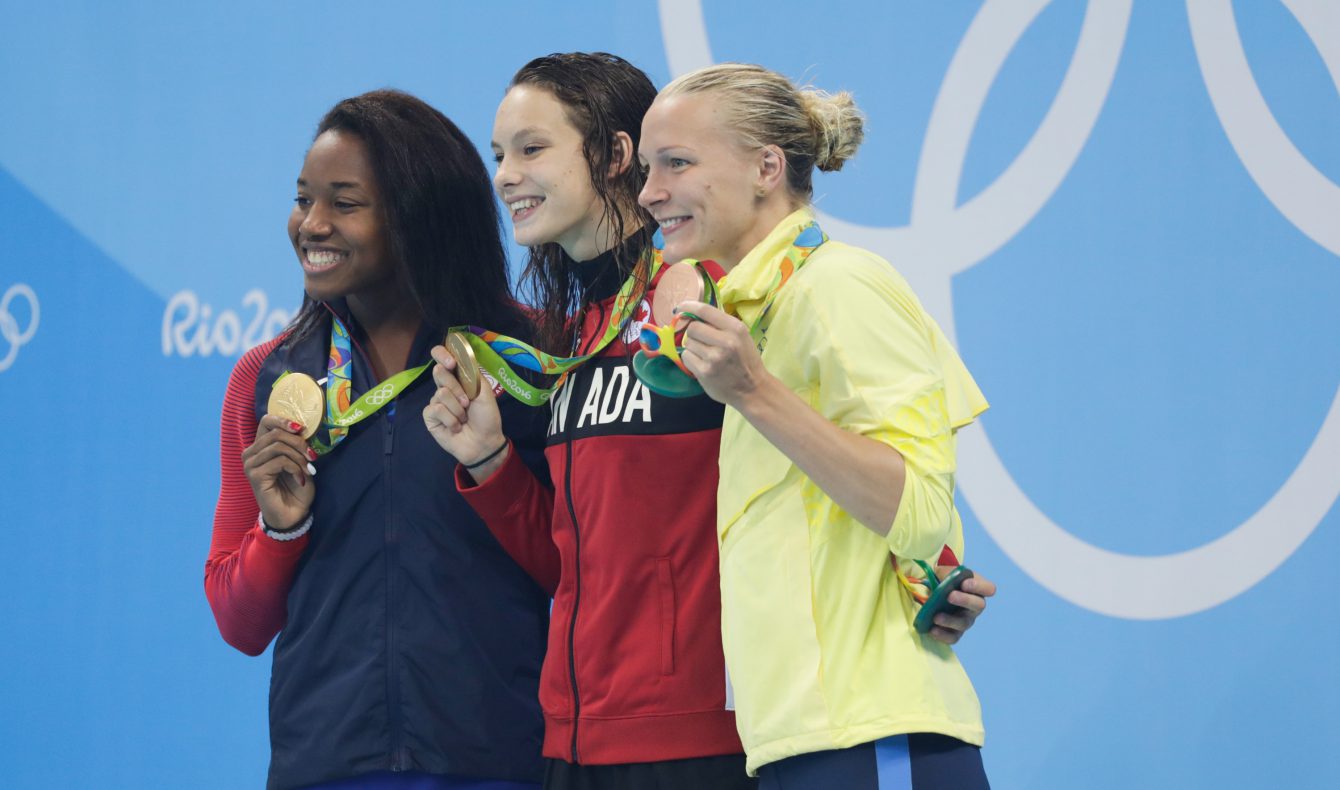 Penny Oleksiak (centre) sur le podium avec sa médaille d'or du 100 m libre aux Jeux de Rio, en compagne de Simone Manuel (or,gauche) et Sarah Sjostrom (bronze, droite). Photo Jason Ransom/COC