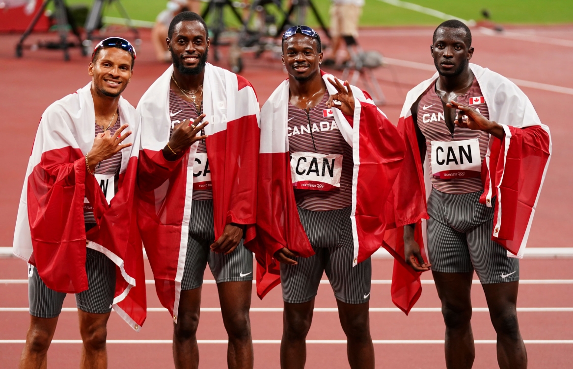 L'équipe du relais masculin 4x100 m pose avec des drapeaux canadiens. 