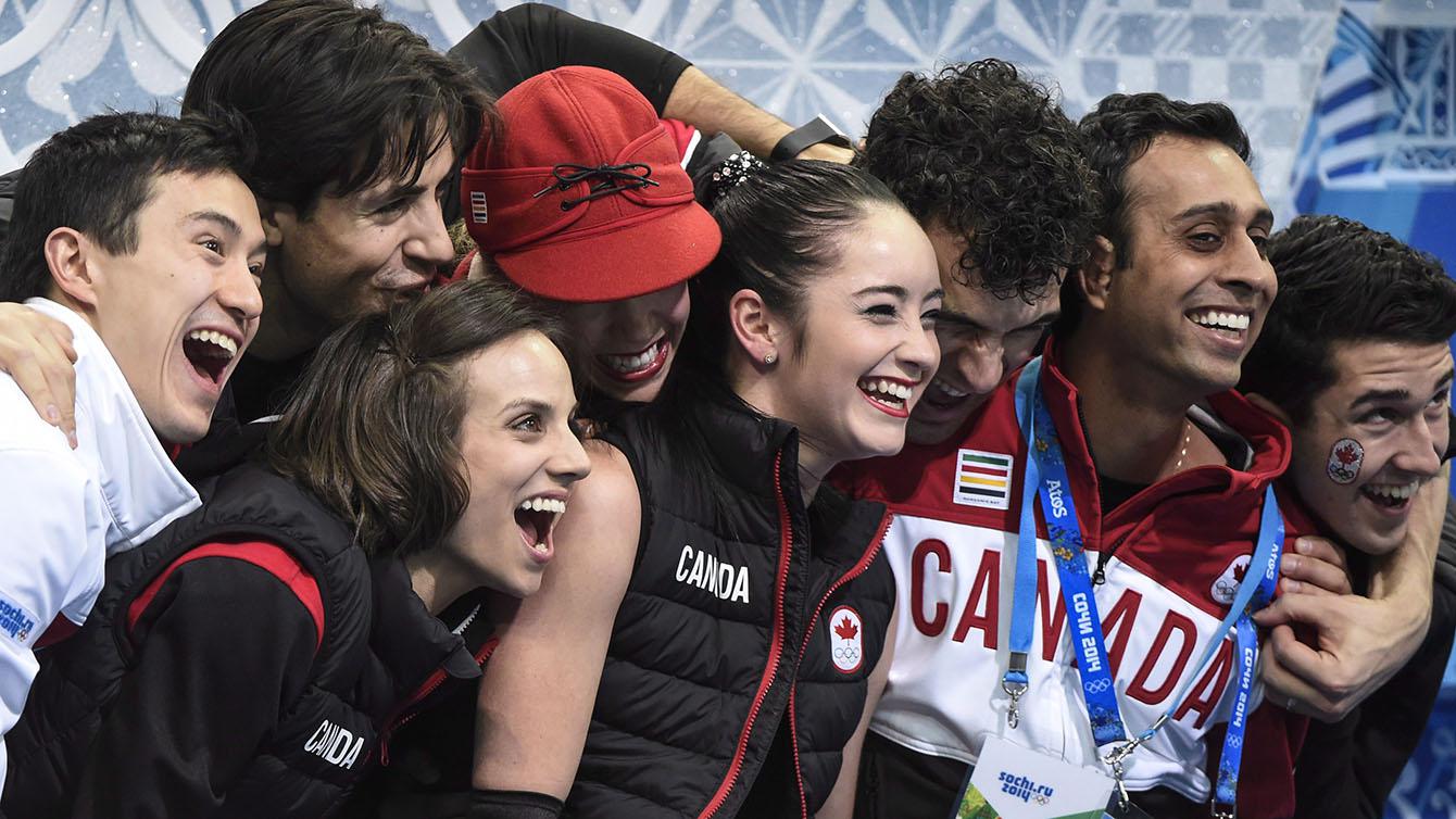 Les membres de l'équipe canadienne entoure Kaetlyn Osmond après son programme court à Sotchi. (PC/Paul Chiasson)