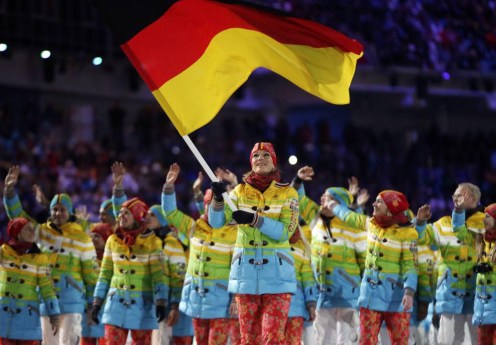 Sandis Ozolins de Lettonie porte le drapeau national et entre dans le stade avec ses coéquipiers lors de la cérémonie d'ouverture des Jeux olympiques d'hiver de 2014 à Sotchi, en Russie, le vendredi 7 février 2014. (AP Photo / Charlie Riedel)