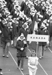 Gaetan Boucher, de Québec, porte le drapeau alors que l'équipe canadienne fait son entrée lors de la cérémonie d'ouverture des XIVe Jeux Olympiques d'hiver à Sarajevo, le 8 février 1984. (Photo PC / Nick Didlick)