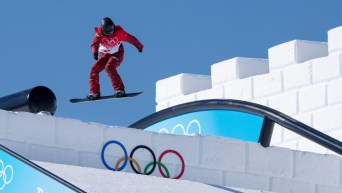 Une athlète de snowboard en plein saut lors d'une descente de slopestyle
