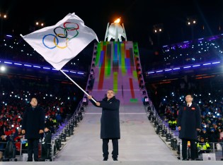 Le président du Comité olympique international, Thomas Bach, brandit le drapeau olympique, accompagné du maire de PyeongChang, Sim Jae-guk (gauche), ainsi que le maire de Beijing, Chen Jining (droite), lors de la cérémonie de clôture. (Kai Pfaffenbach/Pool Photo via AP)
