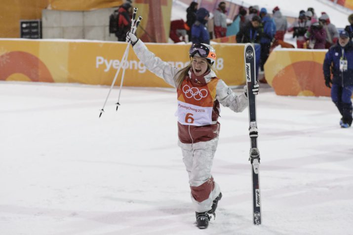 Justine Dufour-Lapointe en bas de la pente, les skis dans la main gauche et les bâtons dans la main droite. 