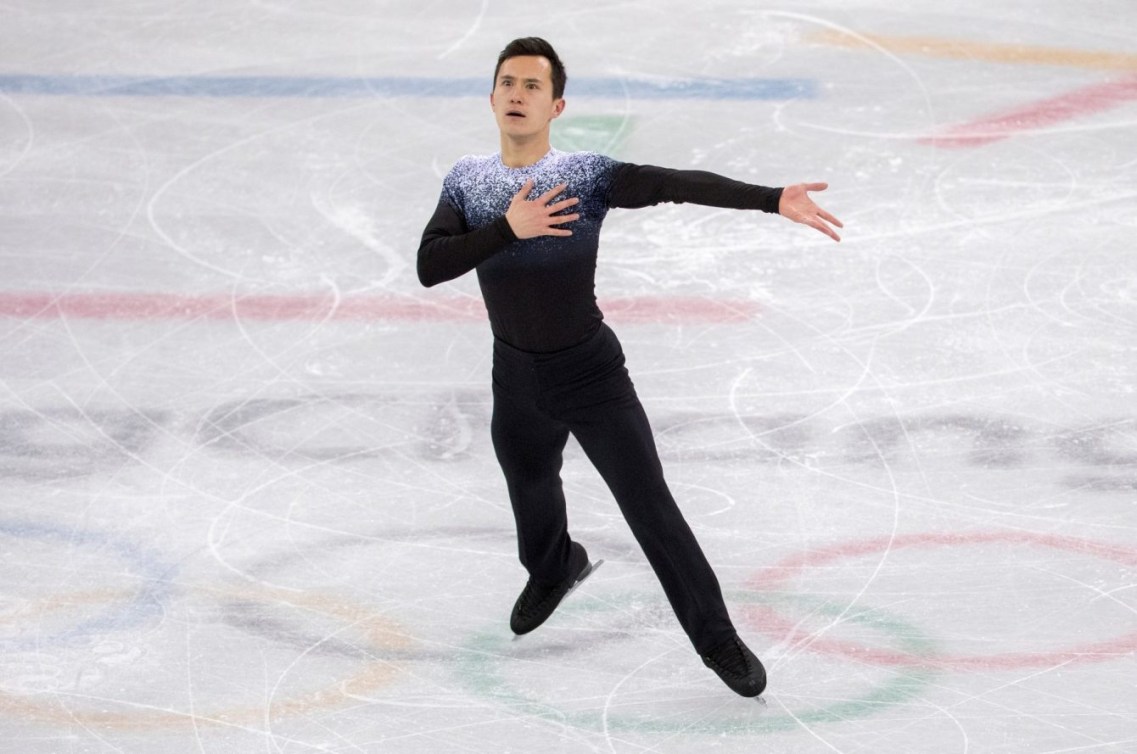 Un patineur artistique sur la glace, une main sur la poitrine.