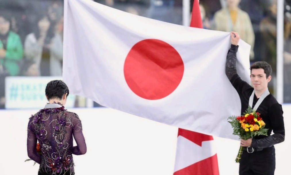 Keegan Messing tient le drapeau Japonais pour Yuzuru Hanyu lors de l'hymne national du Japon.