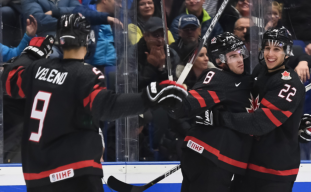 Trois joueurs canadiens célèbrent un but.