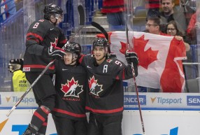 Trois joueurs d'Équipe Canada célèbrent après un but