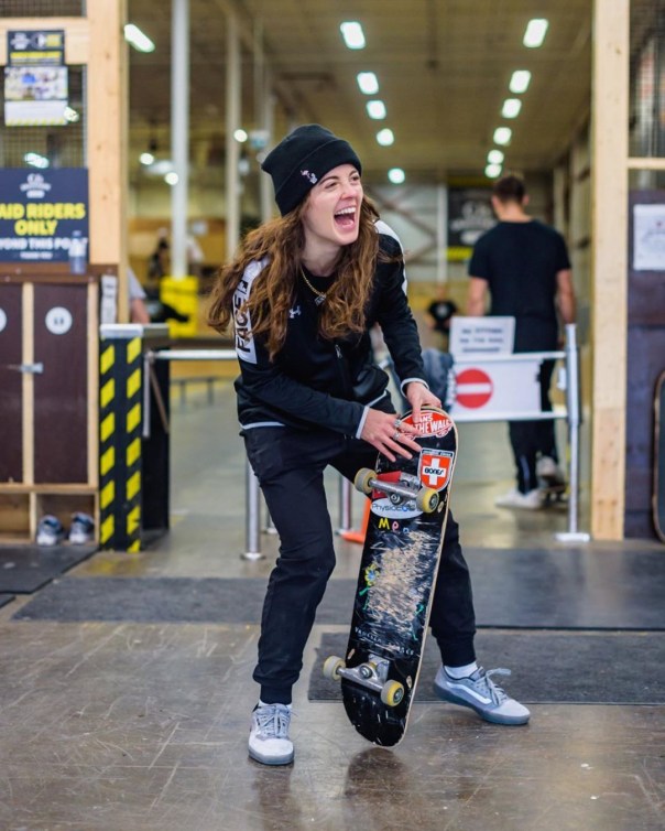 Annie Guglia rit en tenant son skateboard