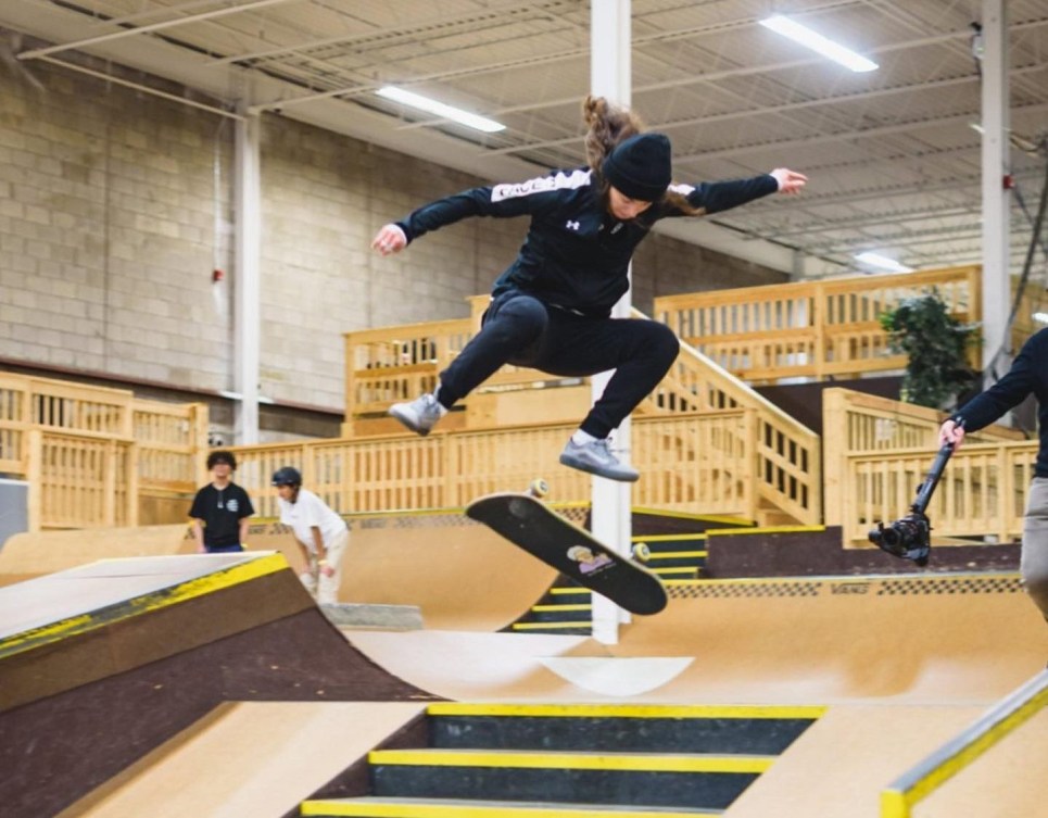 Annie Guglia effectue un saut en skateboard au-dessus d'une rampe.