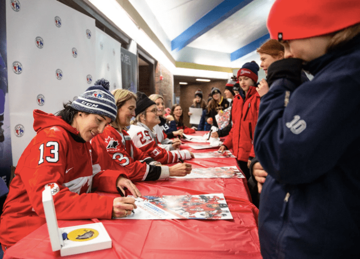 Des hockeyeuses canadiennes signent des autographes.