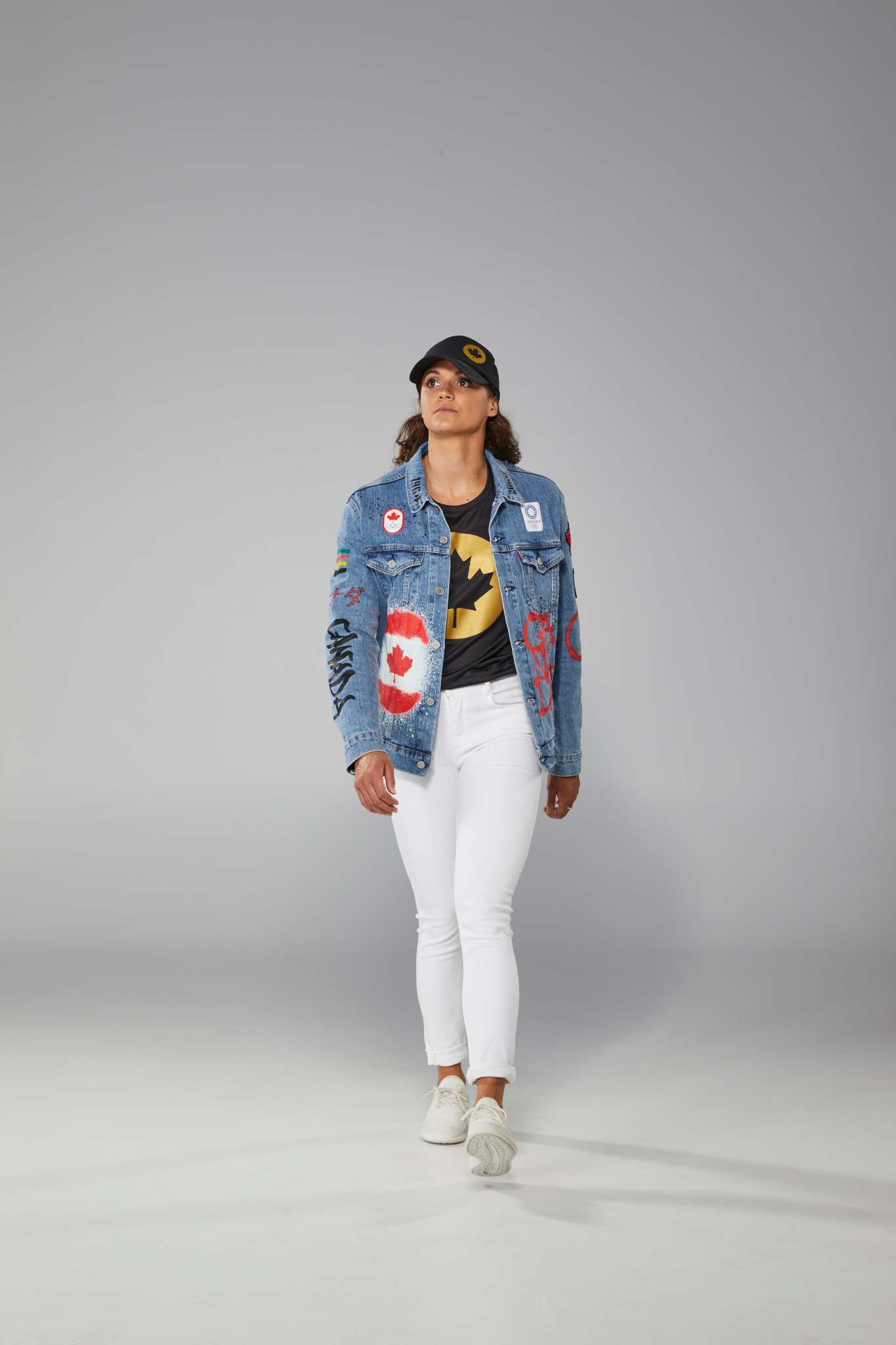 Kylie Masse porte un jeans blanc, un t-shirt noir et une veste en jeans