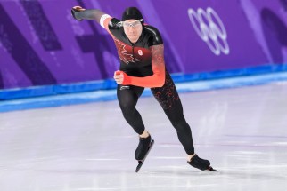 Un patineur de vitesse prend le départ sur un anneau olympique