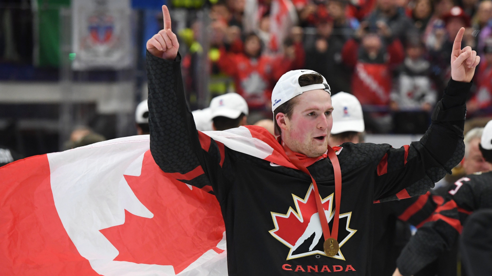 Un joueur de hockey célèbre avec le drapeau canadien porté en cape.