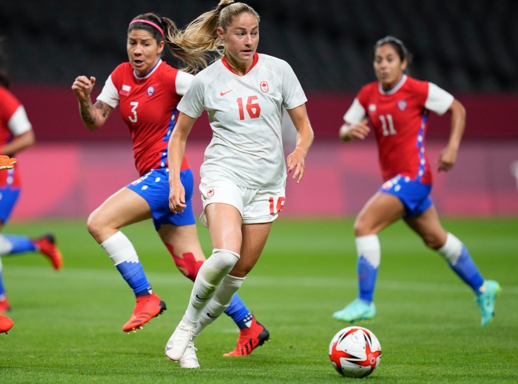 La joueuse canadienne Janine Beckie contrôle le ballon à ses pieds, avec deux joueuses chiliennes en arrière-plan.