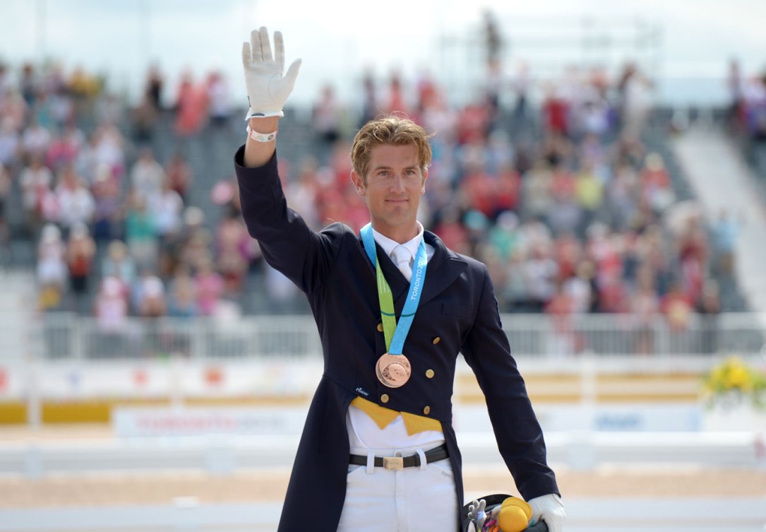 Un athlète de sports équestres salue la foule avec sa médaille