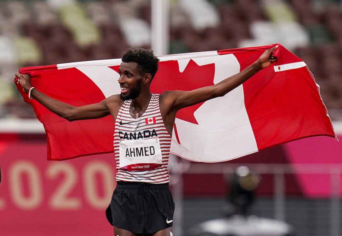 Mohammed Ahmed célèbre sur la piste en tenant le drapeau canadien. 