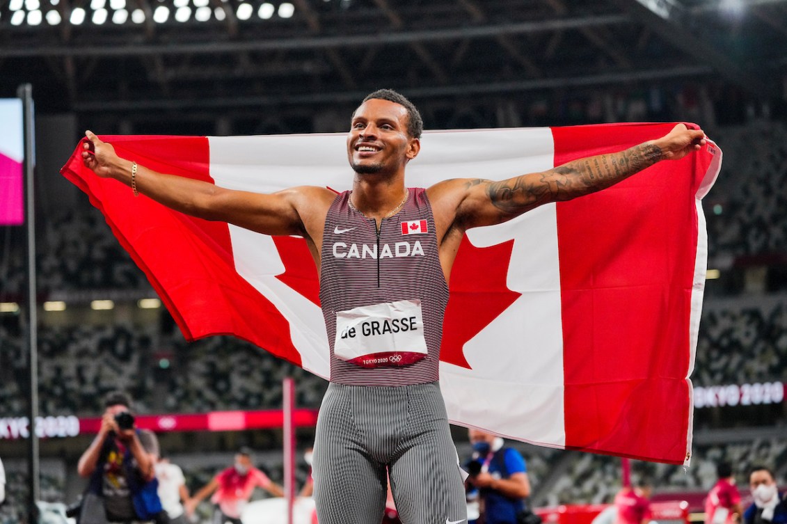 Andre De Grasse tient un drapeau canadien. 