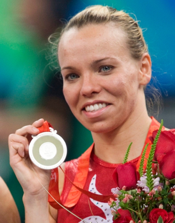 Une athlète pose pour la caméra avec sa médaille d'argent des Jeux olympiques de 2008 dans la main droite.