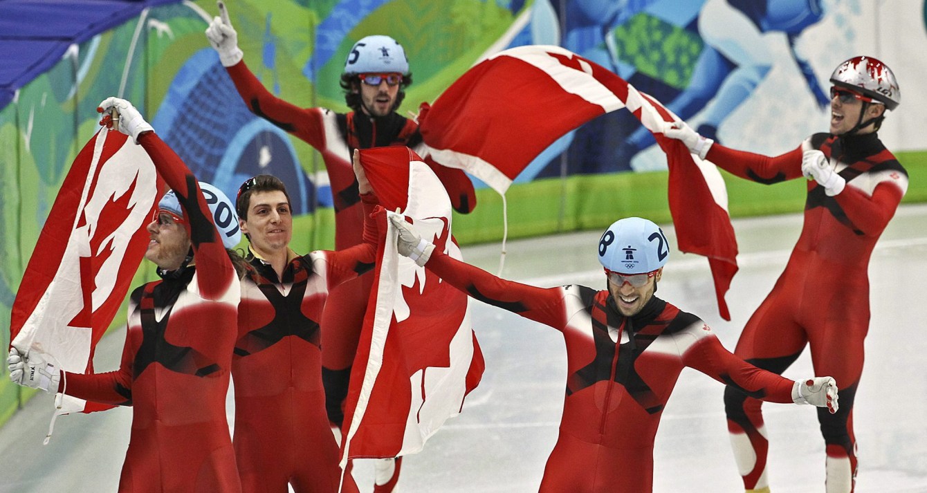 L'équipe masculine de relais de patinage de vitesse courte piste célèbre à Vancouver 2010. Les patineurs font un tour d'honneur des drapeaux canadiens dans les airs. 