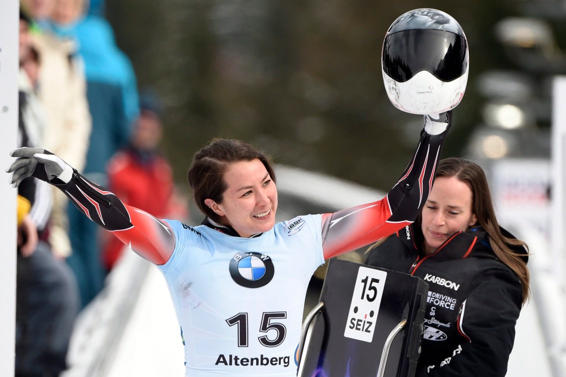 Jane Channell souriante a les deux bras dans les airs et son casque dans la main gauche. 