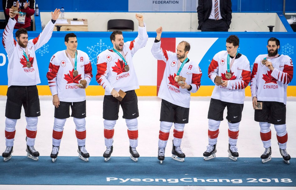 Des joueurs de hockey célèbre sur le podium olympique.