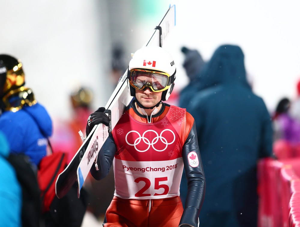 Un sauteur à ski marche avec son équipement