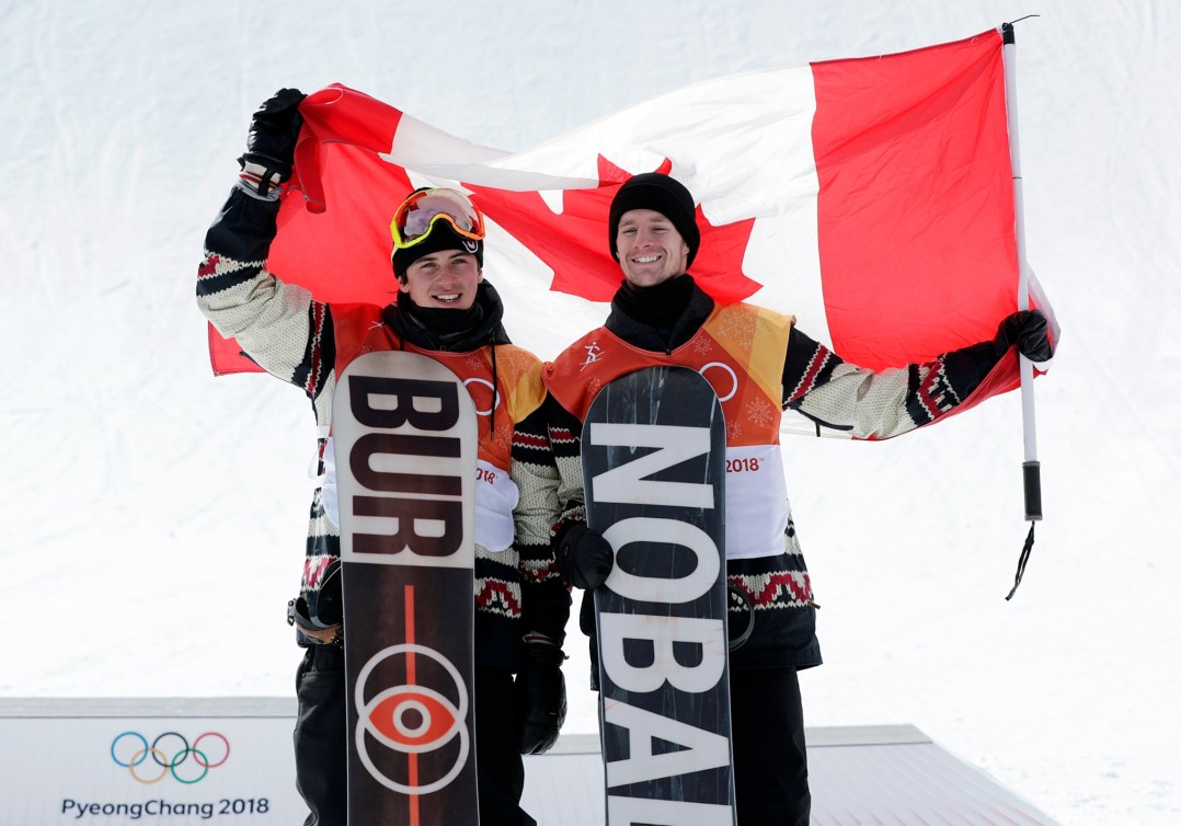 Deux planchistes brandissent le drapeau du Canada sur le podium