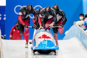 Justin Kripps, Ryan Sommer, Cam Stones et Benjamin Coakwell poussent leur bob à touter vitesse et s'apprêtent à y embarquer lors de l'épreuve de bobsleigh à quatre de Beijing 2022.