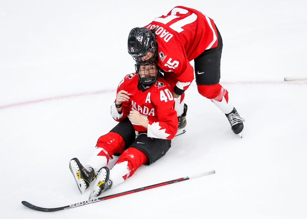 Une hockeyeuse tient sa coéquipière blessée.