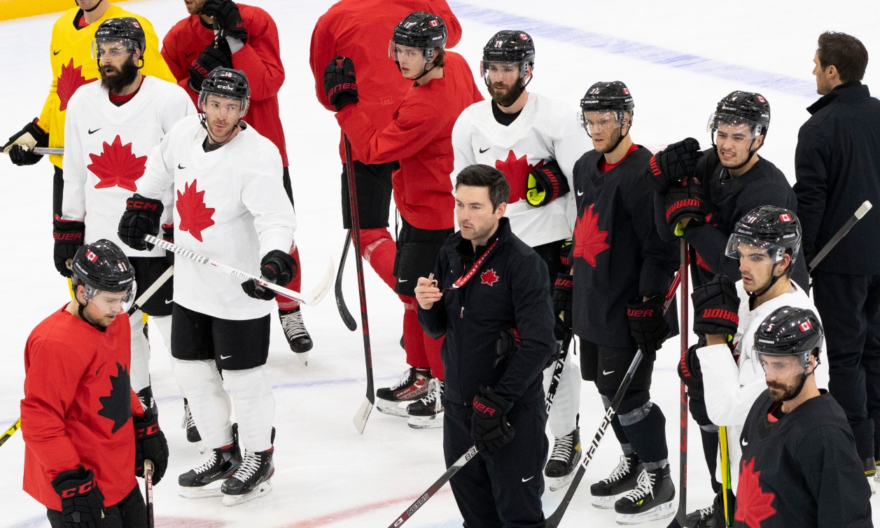 L’entraîneur-chef Jeremy Colliton, encerclé par les membres de l'équipe, dirige un entraînement sur glace à Beijing 2022.
