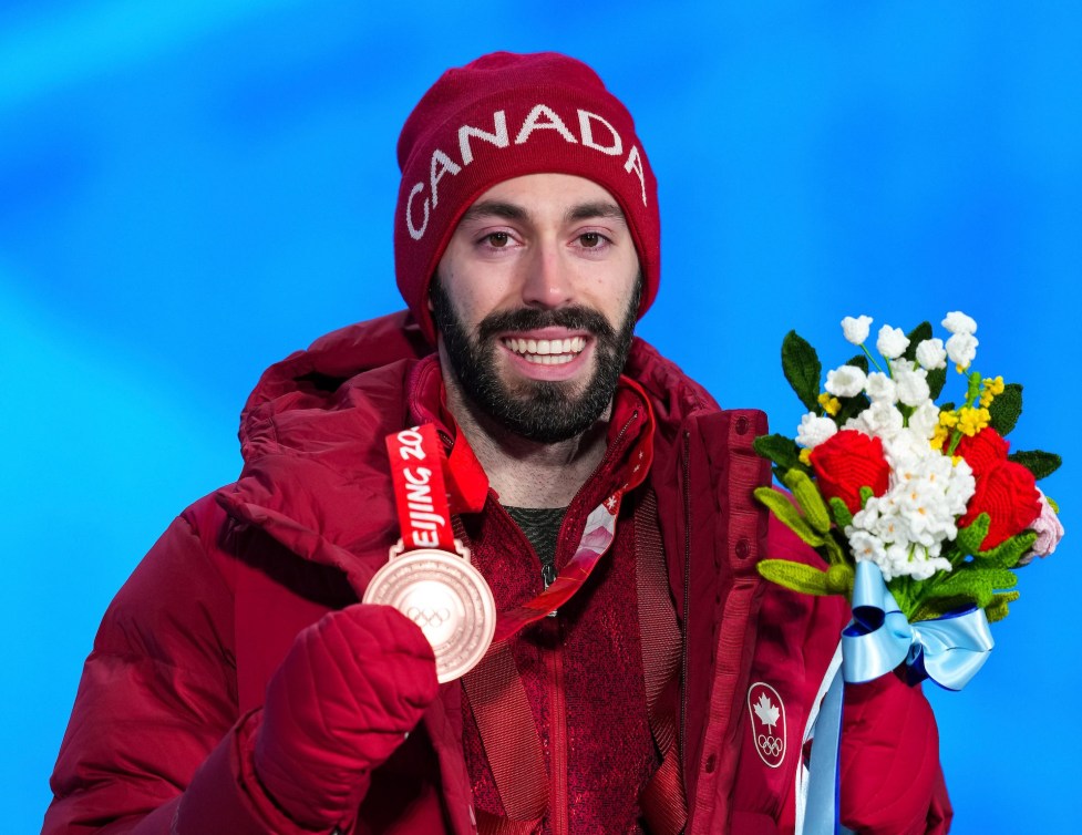 Steven Dubois avec ses fleurs dans la main gauche et sa médaille dans la main droite.