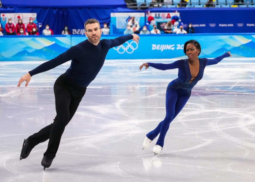 Le duo Vanessa James et Eric Radford patinent côte à côte en étendant les bras à Beijing 2022.