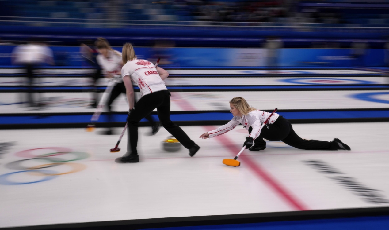 Jennifer Jones lance une pierre devant elle avec ses collègues à ses côtés qui se préparent à balayer la glace lors du match contre la Suisse à Beijing 2022