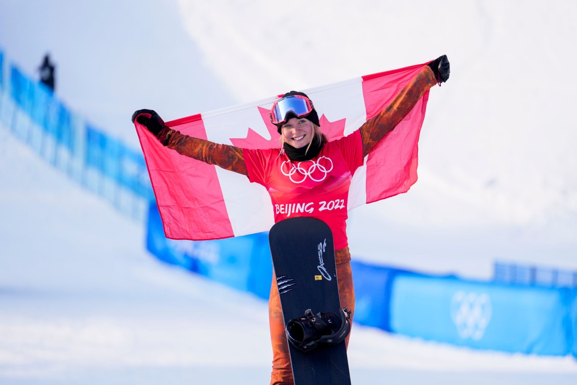 Meryeta O'Dine tient un drapeau canadien à bout de bras, sa planche à la verticale devant elle. 