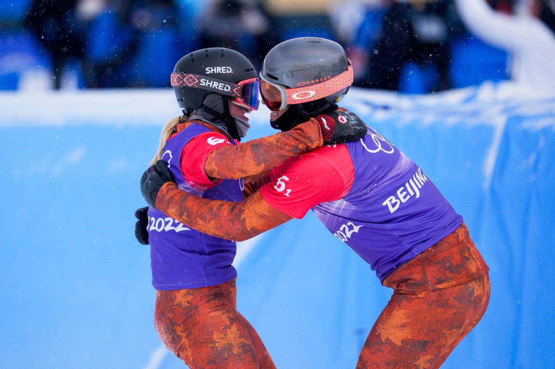Eliot Grondin et Meryeta O'Dine célèbrent leur médaille de bronze en se serrant dans les bras à la fin de l'épreuve de snowboard cross par équipes mixtes à Beijing 2022.