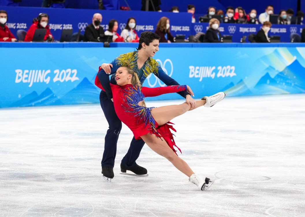 Marjorie Lajoie se laisse tomber dans les bras de Zachary Lagha et étirant les jambes, Lagha prend son tibia gauche, à Beijing 2022.