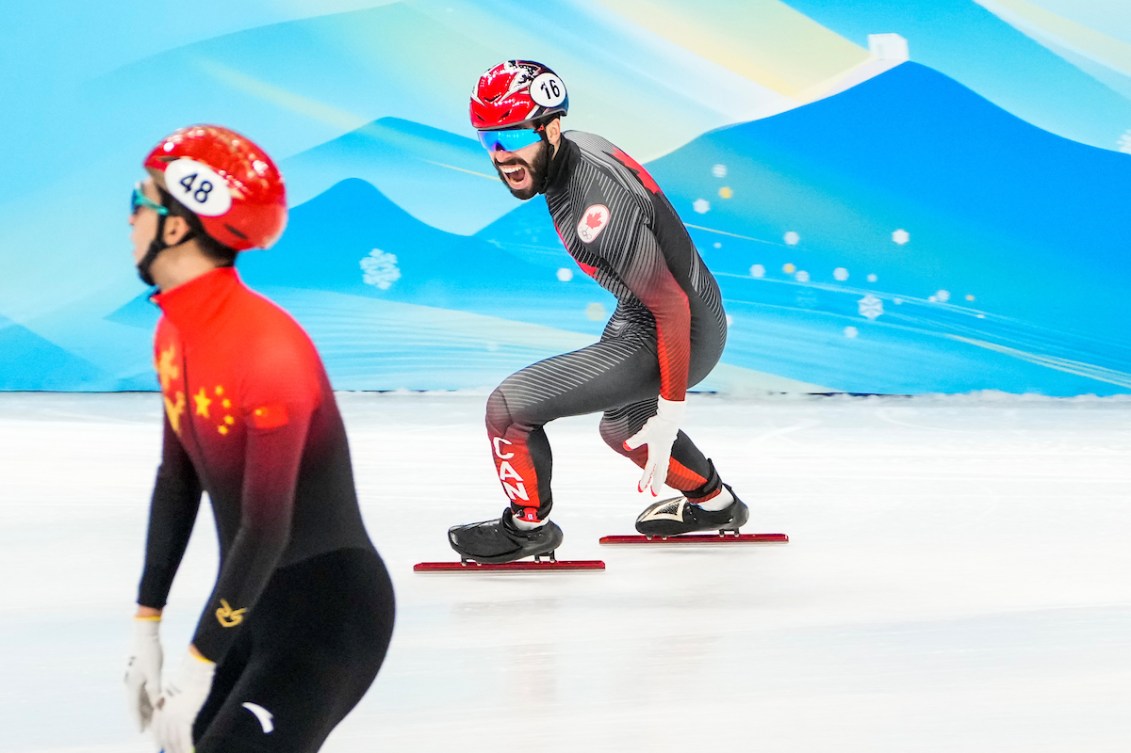 Steven Dubois crie de joie sur la glace après avoir remporté la médaille d'or avec son équipe au relais du 5000 mètres en patinage de vitesse sur longue piste.