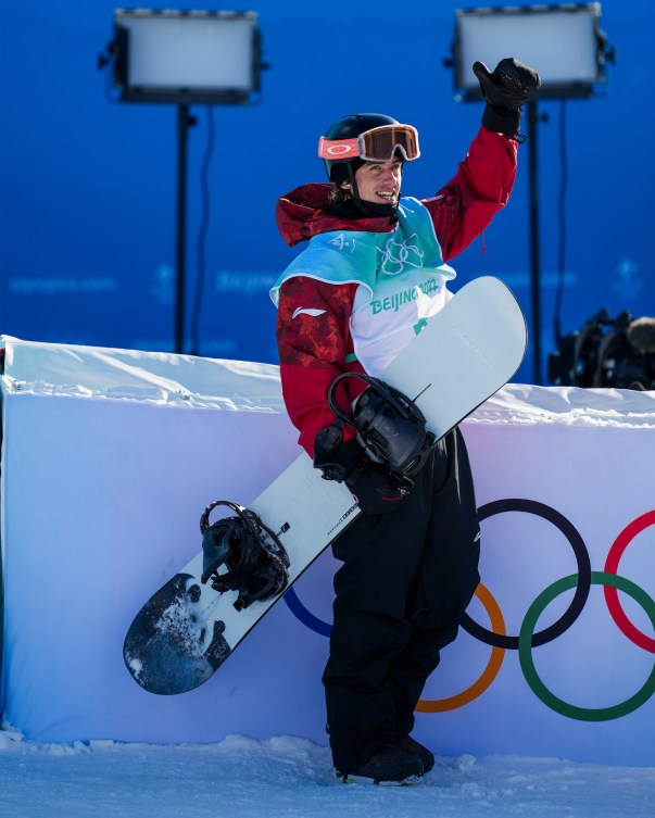 Le planchiste d'Équipe Canda Mark McMorris lève le pouce gauche dans les airs en tenant sa planche dans l'autre main après sa performance au big air à Beijing 2022.