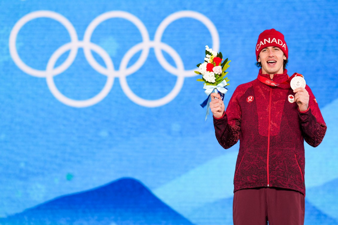 Le planchiste Mark McMorris d'Équipe Canada tient sa médaille de bronze avec la main gauche et son bouquet de fleurs de la main droite sur le podium du slopestyle masculin en snowboard de Beijing 2022.