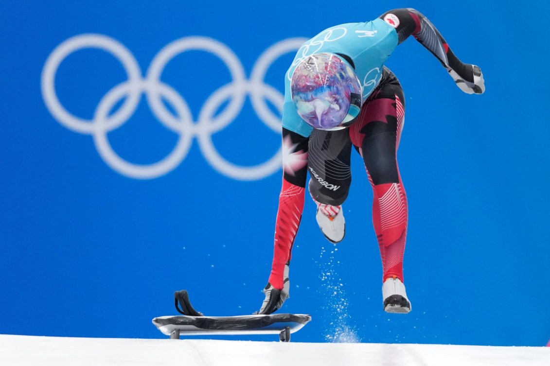 La Canadienne Mirela Rahneva tient son skeleton d'une main et court à côté de celui-ci au départ d'un entrainement en skeleton féminin à Beijing 2022. 
