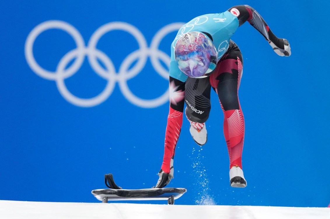 La Canadienne Mirela Rahneva tient son skeleton d'une main et court à côté de celui-ci au départ d'un entrainement en skeleton féminin à Beijing 2022.