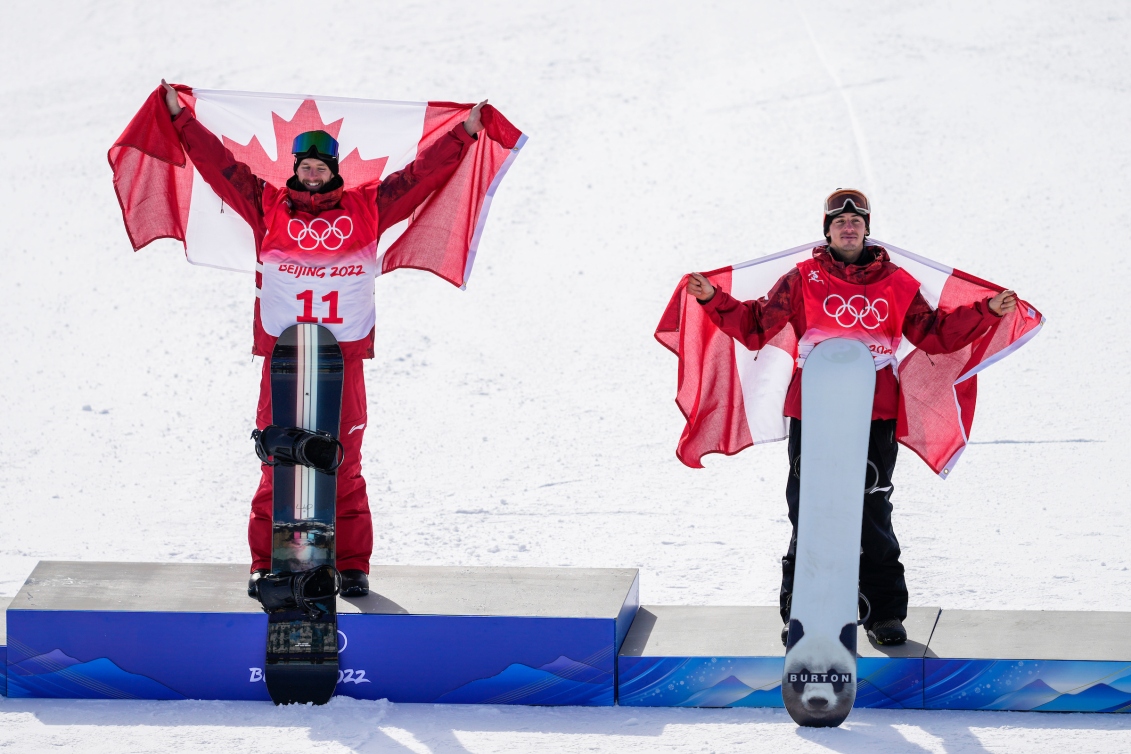 Les planchistes canadiens Max Parrot et Mark McMorris sur le podium du slopestyle masculin àa Beijing 2022. Les deux Canadiens sont drapés du drapeau canadien.