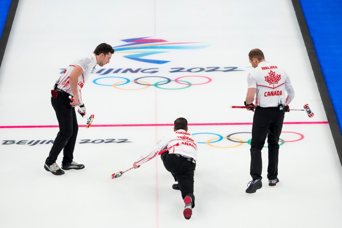Brad Gushue lance une pierre sur la glace avec Brett Gallant et Geoff Walker à ses côtés