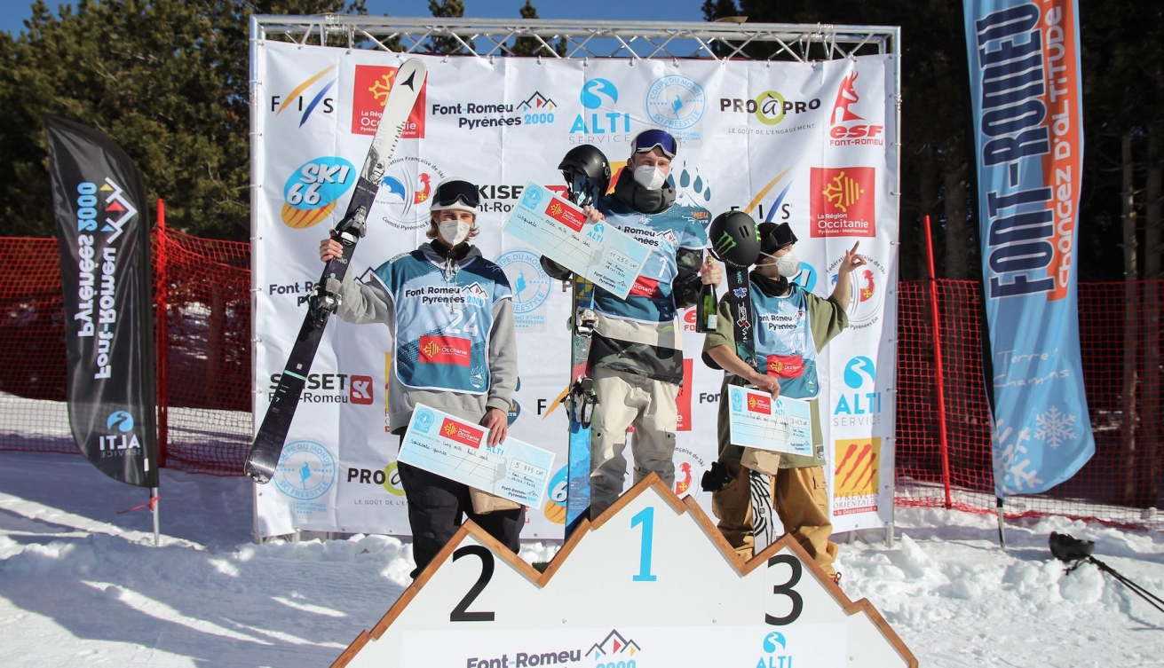 Édouard Therriault sur la troisième marche du podium, ses skis à la main.